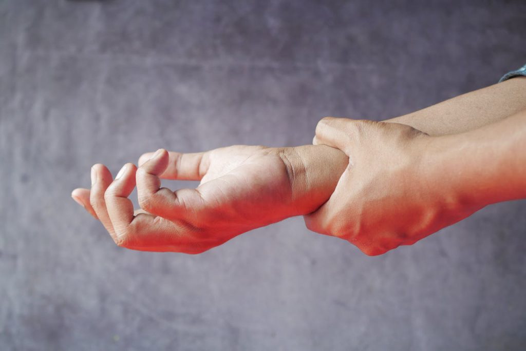 Person holding wrist due to muscle tension, showing stress-related pain that physiotherapy can relieve during winter