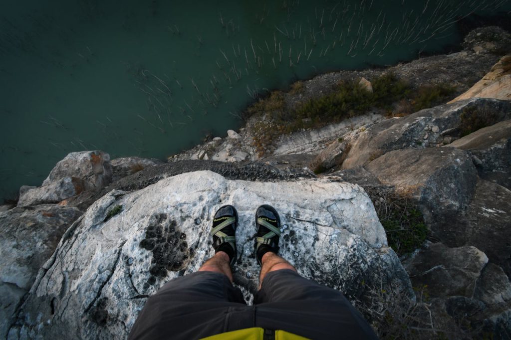 First-person view looking down a steep cliff edge, illustrating the spinning sensation, unsteadiness, and fear of falling experienced by patients with vertigo and balance disorders.