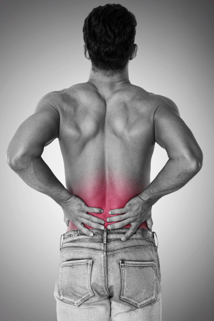 Man holding lower back showing pain area related to slipped disc or muscle strain