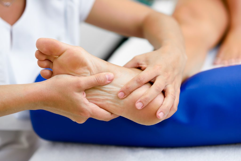 Physiotherapist holding a patient’s foot to assess ankle movement and strength during a foot drop examination